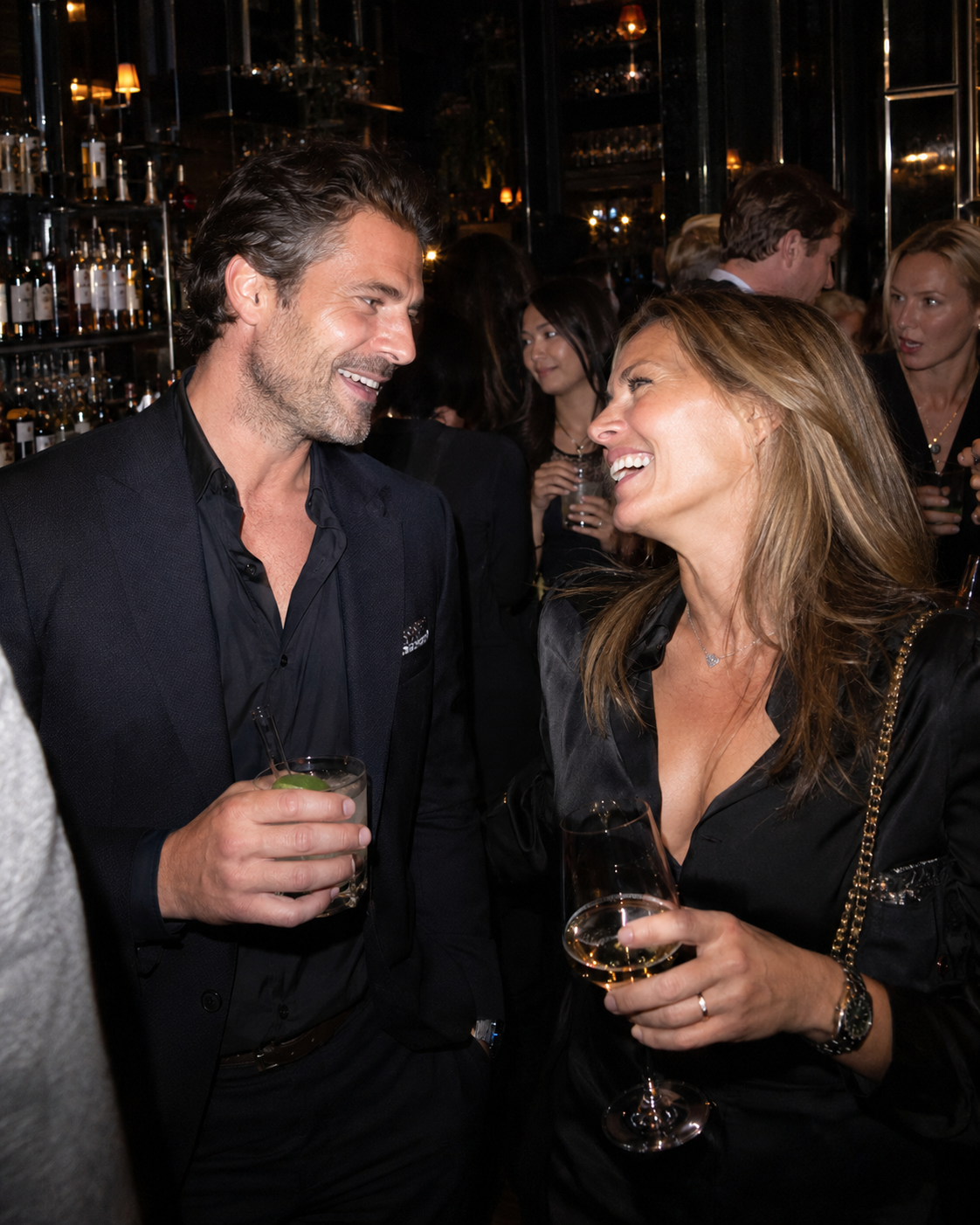 A man and a woman laughing together at a candlelit bar